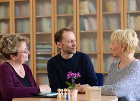 Drei Personen unterhalten sich in einem Beratungsgespräch zum Thema Familienhilfe.