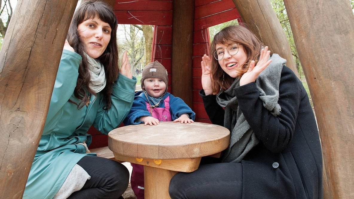 Zwei junge Frauen mit einem kleinen Jungen auf dem Spielplatz.