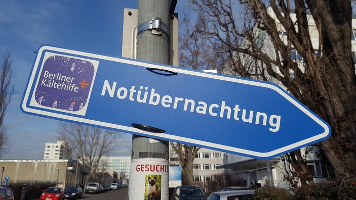 Ein Wegweiser als Verkehrsschild, auf dem steht "Notübernachtung".