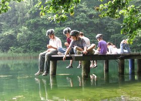 Erlebnispädagogik: Jugendliche sitze auf einem Steg am See